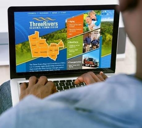 Person looking at the latest news on projects by the Three Rivers Regional Commission on a laptop computer